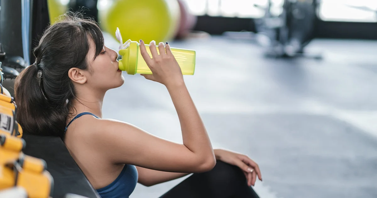 woman drinking an electrolyte supplement at the gym